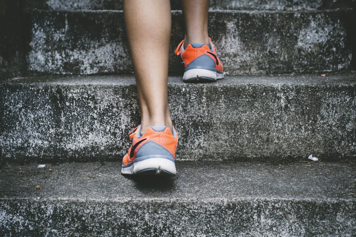 Person in Laufschuhen steigt eine Steintreppe hinauf